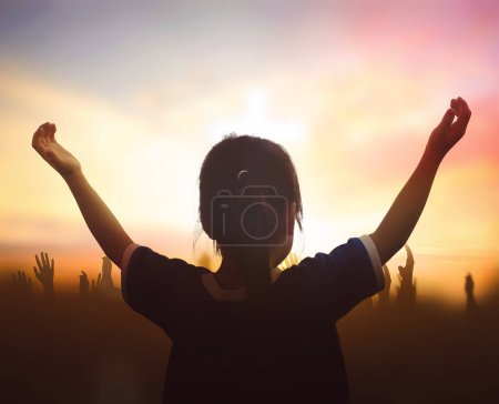 Téléchargez les photos : Mains levées pour adorer Dieu sur une croix floue au coucher du soleil - en image libre de droit