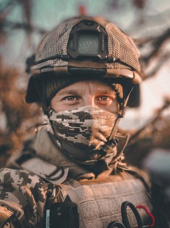 Photo for Powerful portrait of a 37-year-old Ukrainian military soldier in full body armor, ballistic helmet, and protective goggles, staring straight into the camera with a calm and focused expression. - Royalty Free Image
