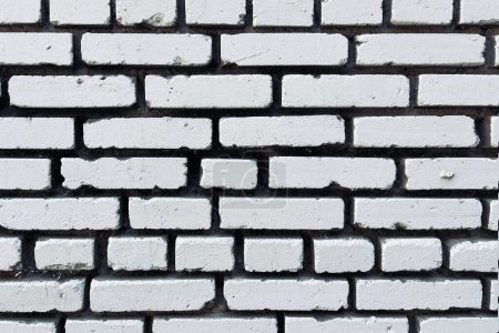 Close-up of a white-painted brick wall, showing detailed texture and imperfections in the paint and bricks, ideal for backgrounds or textural contrasts