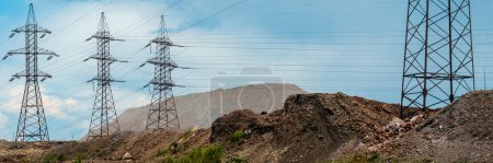 A wide panoramic view of an industrial landscape with power lines and mounds of waste materials. environmental impact of industrial activities, including pollution and waste management.