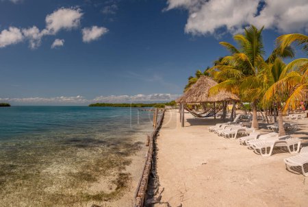 Belichtung auf einer Insel in Belize, die die Vegetation und Palapas dieser wunderschönen Karibik-Insel Belize mit einer wunderschönen Meeresfarbe zeigt.