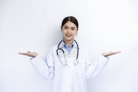 Téléchargez les photos : Une femme médecin en robe blanche pose avec un espace vide en arrière-plan pour le texte publicitaire. - en image libre de droit