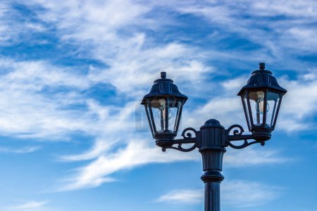 Lamppost on the background of blue sky and white clouds