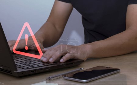 Foto de Empresario que usa computadora portátil con señal de advertencia de triángulo para alerta de error y concepto de mantenimiento Protección de datos de piratas informáticos - Imagen libre de derechos