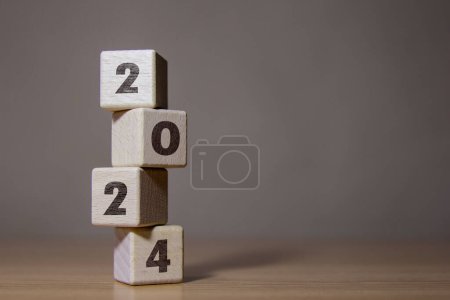 Los números 2024 en bloques de madera apilados verticalmente. Las ideas empresariales se transforman en nuevos éxitos Avanzar hacia el éxito en 2024
