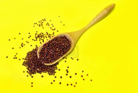 Photo for Red Quinoa seeds in wooden Spoon on yellow background. Top view. - Royalty Free Image