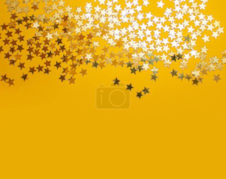 Foto de Confitería de estrellas doradas sobre fondo amarillo. Piso tendido, vista superior. - Imagen libre de derechos