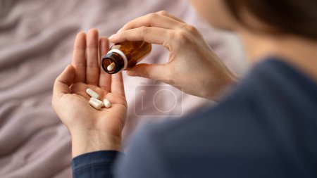 Photo for Closeup of woman hand pouring capsules from a pill bottle into hand - Royalty Free Image