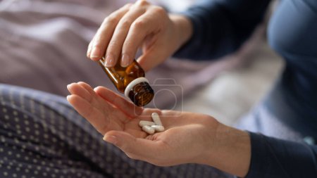 Téléchargez les photos : Gros plan de la main de la femme versant des capsules d'un flacon de pilule dans la main - en image libre de droit