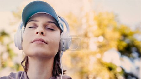 Téléchargez les photos : Femme écoutant de la musique avec des écouteurs dans la nature - en image libre de droit