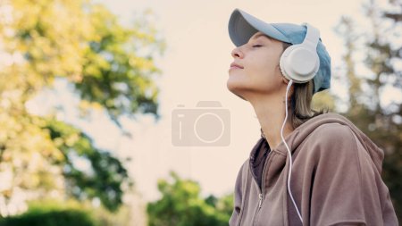 Téléchargez les photos : Femme écoutant de la musique avec des écouteurs dans la nature - en image libre de droit