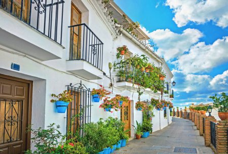 Foto de Pintoresca calle estrecha y típica fachada de casa blanca decorada con macetas azules en Mijas. Málaga provincia, Andalucía, España - Imagen libre de derechos