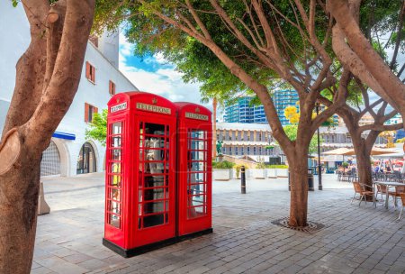 Photo for Cityscape with two English red telephone boxes on pedestrian main street at centre of town. Gibraltar, Europe - Royalty Free Image