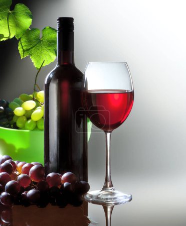 Foto de Bodegón con copa de vino y botella de vino tinto y uva de rama sobre fondo claro - Imagen libre de derechos