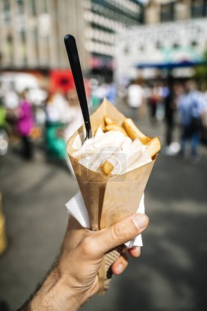 Téléchargez les photos : Frites frites street food avec sauce à la main sur le fond du marché alimentaire. Photo de haute qualité - en image libre de droit