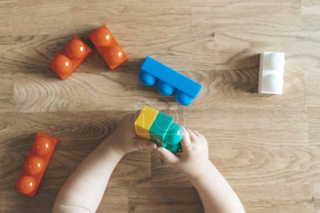 Téléchargez les photos : Développement de l'enfant. Des blocs de jouets Montessori et un enfant, un bébé qui joue. Développement précoce, maternelle, concept d'enfance. Photo de haute qualité - en image libre de droit