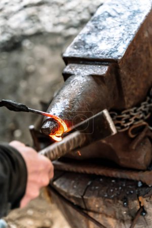 Herrero en una fragua trabajando en un yunque. Forja de metal caliente. Foto de alta calidad