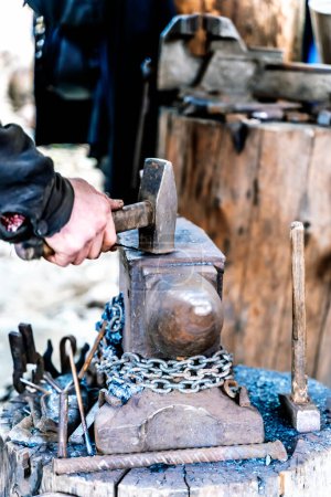 Herrero en una fragua trabajando en un yunque. Forja de metal caliente. Foto de alta calidad