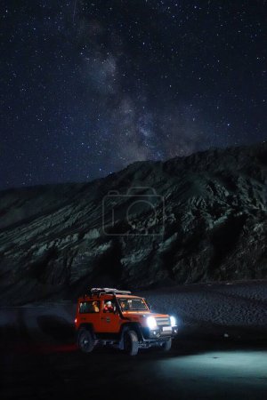 Foto de Ladakh, India - August 24th, 2022: Extreme long exposure image showing Milkyway Galaxy over an SUV offroad vehicle in the mountains of Himalayas. - Imagen libre de derechos