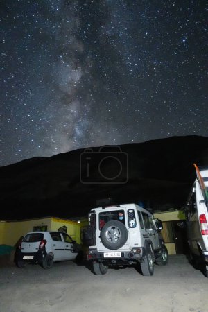 Foto de Ladakh, India - August 24th, 2022: Extreme long exposure image showing Milkyway Galaxy over an SUV offroad vehicle in the mountains of Himalayas. - Imagen libre de derechos