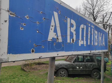 Foto de Signo de bala dañada con la inscripción "Avdiivka" y un vehículo militar - Imagen libre de derechos