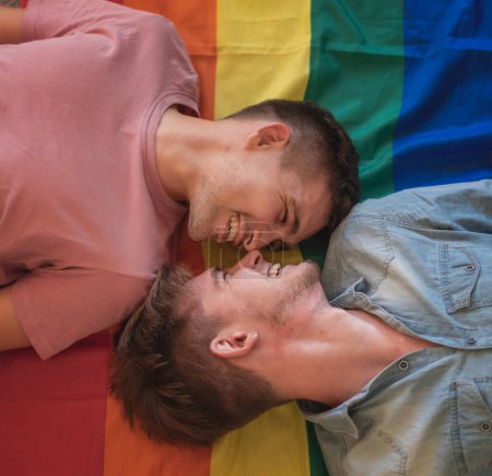 Foto de Retrato de pareja gay joven abrazando y mostrando su amor con la bandera del arco iris - Imagen libre de derechos