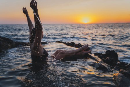 Téléchargez les photos : Jeune femme joyeuse et détendue dans un bain de mer naturel au bord de la mer. Thalassothérapie et bien-être - en image libre de droit