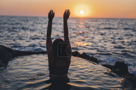 Téléchargez les photos : Silhouette d'une femme aux mains levées sur la plage de la mer au coucher du soleil. Photo de haute qualité - en image libre de droit