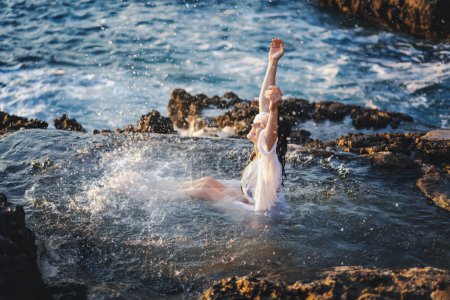 Téléchargez les photos : Jeune femme joyeuse et détendue en chemise blanche dans un bain de mer naturel au bord de la mer. Thalassothérapie bien-être - en image libre de droit