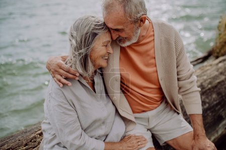 Photo for Senior couple sitting and having romantic moment at the autumn sea. - Royalty Free Image