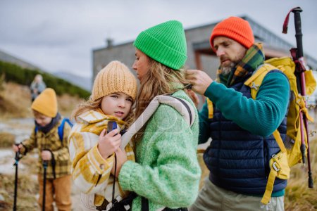 Foto de Hombre ayudando a su esposa con su pequeña hija cansada, dándola en el portador de niños, durante la caminata de otoño en las montañas. - Imagen libre de derechos