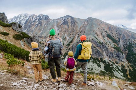 Téléchargez les photos : Vue arrière de la famille avec de petits enfants lors de la randonnée d'automne dans les montagnes. Concept de mode de vie sain. - en image libre de droit