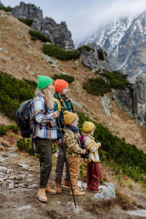 Foto de Vista lateral de la familia con niños pequeños en la caminata de otoño en las montañas. Concepto de estilo de vida saludable. - Imagen libre de derechos