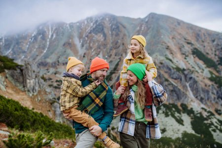 Téléchargez les photos : Des parents heureux avec leurs petits enfants sur le dos lors d'une randonnée automnale, au milieu des montagnes. Concept de mode de vie sain. - en image libre de droit