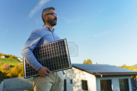 Téléchargez les photos : Homme d'affaires tenant un panneau solaire, debout à l'extérieur dans un jardin. - en image libre de droit