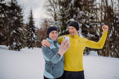 Photo for Senior couple taking selfie during jogging in snowy nature. - Royalty Free Image