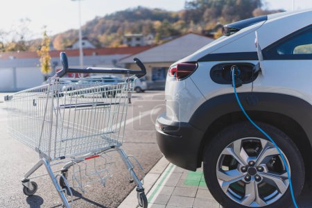 Téléchargez les photos : Chargement de voiture électrique moderne dans un parking de supermarché. - en image libre de droit