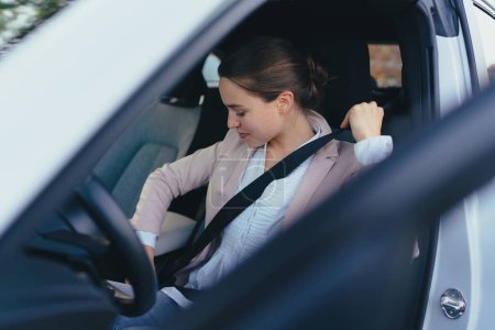 Mujer joven que da cinturón de seguridad en el coche, la preparación para una conducción, el concepto de una conducción de seguridad.