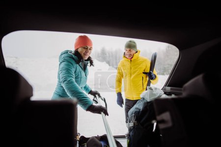 Téléchargez les photos : Couple aîné près d'un coffre de voiture se préparant pour le ski d'hiver. - en image libre de droit