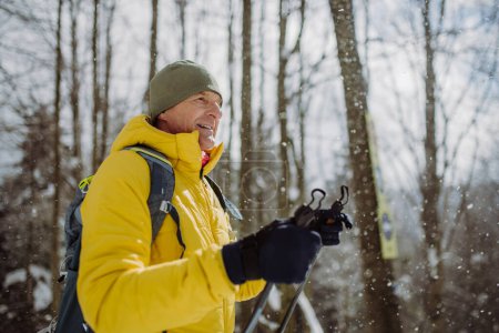Téléchargez les photos : Homme âgé admirant la nature pendant le ski de fond en forêt. - en image libre de droit