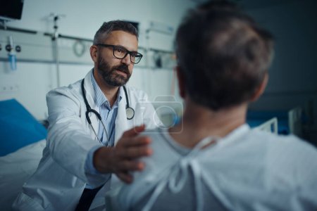 Photo for Mature doctor consoling and explaining diagnosis to his patient in hospital room. - Royalty Free Image