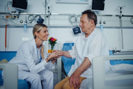 Téléchargez les photos : Jeune femme médecin tenant la main, et parlant avec sa patiente dans la chambre d'hôpital. - en image libre de droit