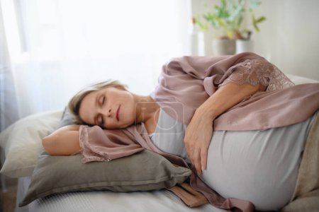 Téléchargez les photos : Femme enceinte dormant et se reposant dans un lit. - en image libre de droit