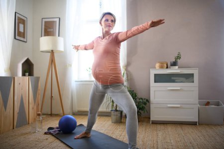 Téléchargez les photos : Femme enceinte faisant les exercices dans son appartement. - en image libre de droit