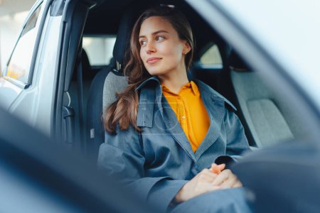 Photo for Excited young woman sitting in a car, waiting for somebody. - Royalty Free Image