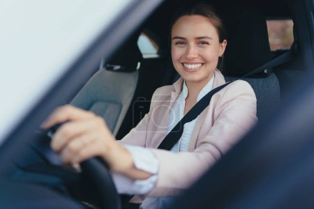 Mujer joven emocionada sentada en su coche, preparada para conducir.