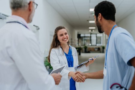 Photo for Close-up of doctors shaking hands at a hospital corridor. - Royalty Free Image