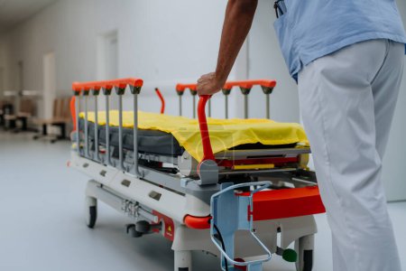 Foto de Vista trasera del cuidador empujando la cama del hospital en un pasillo. - Imagen libre de derechos