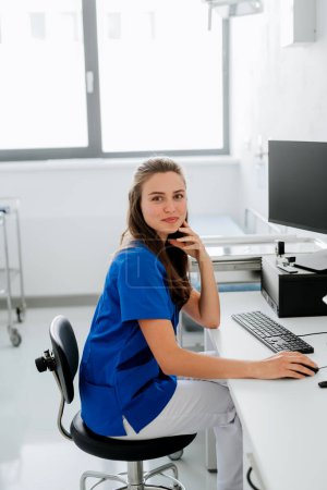 Photo for Young woman doctor sitting at a hospital office desk. - Royalty Free Image