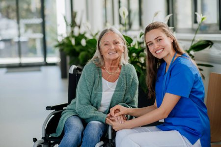 Photo for Young woman doctor taking care of senior woman at a wheelchair. - Royalty Free Image